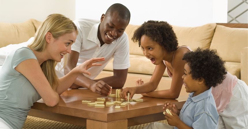 A family laughs while playing dominoes.