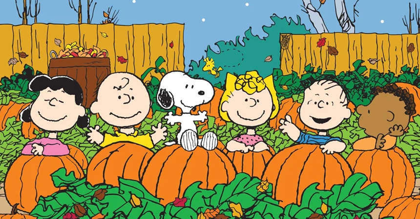 The cast of "Peanuts" stands smiling in a pumpkin patch.