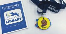 a photo of the Klamath Library Passport - a zine-sized booklet, and the accompanying lanyard with brag tags.
