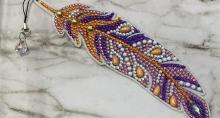 A piece of plastic shaped like a stylized feather, covered on one side by Rhinestone-style gem stickers.