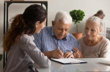 A young woman chats with an older couple as the older couple signs paperwork.