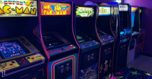 A row of retro arcade machines: Super Pac-Man, Ms. Pac-Man, Galaga, TRON and BurgerTime.