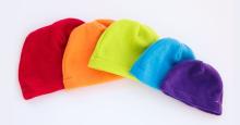 A rainbow assortment of simple fleece beanies in a variety of sizes.