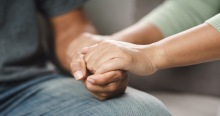 A photo focused on the hands of someone comforting another person.