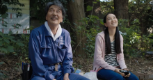 Actors Koji Yakusho and Arisa Nakano look up at the sky with dreamy expressions in a scene from Perfect Days.
