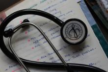 A doctor's stethoscope lying on a page of medical notes.