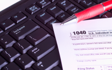 A photograph of a 1040 tax form lying on top of a computer keyboard.