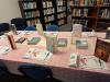 Table with a book, a paper placemat and a pen at each seating place